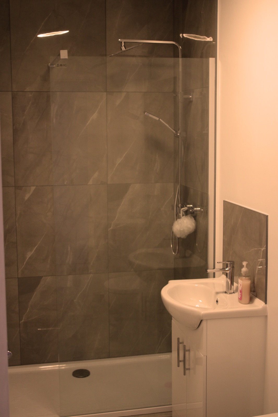 Modern private shower room with dark marble tiles, rainfall head and clean vanity